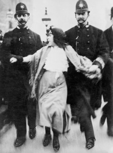A 'Lancashire lassie' being escorted through the palace yard, Westminster Palace, London, 20th March 1907. A young woman is reluctantly escorted by two policeman who are holding her by the arms. The woman is still protesting as she is led away. The last line of the verse at the bottom says 'For Women's Rights anything we will dare; Palace Yard, take me there!' (Photo by Museum of London/Heritage Images/Getty Images)